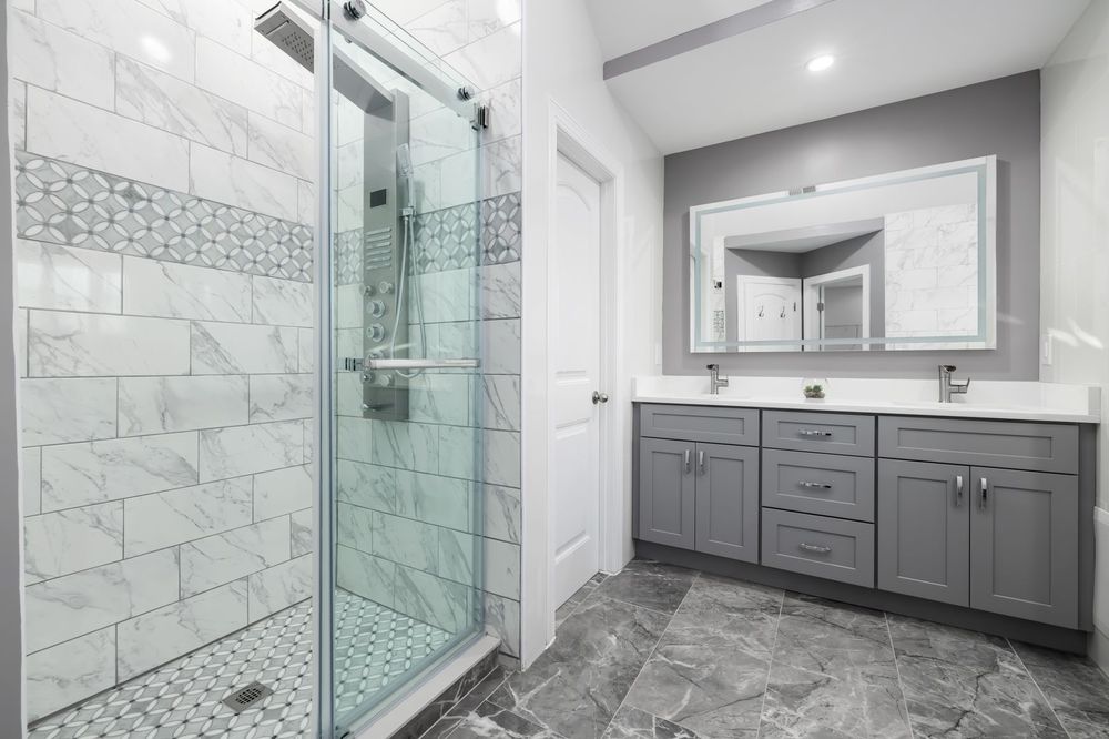 Bathroom with a glass walk-in shower, marble-look tile and a gray double vanity