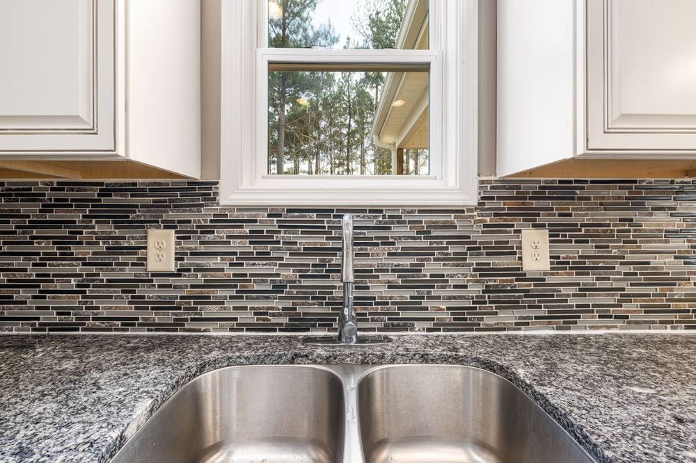 Granite countertop with an undermount sink and a glass mosaic backsplash